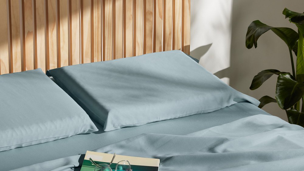 Sunlit blue pillows on a made bed